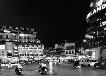 People on street against illuminated city at night