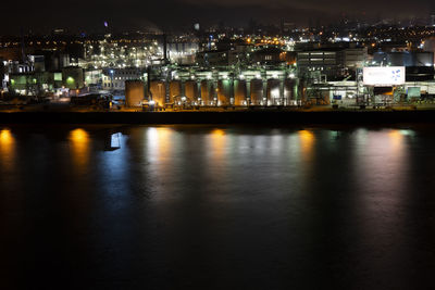 Illuminated bridge over river in city at night