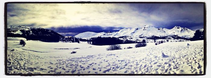 Scenic view of snow covered mountains against cloudy sky