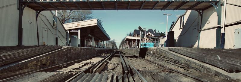 Railroad tracks by old building in city against sky