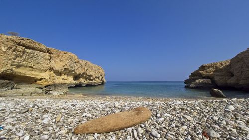 Rocks on beach against clear blue sky