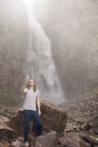 Man taking selfie in front of waterfall