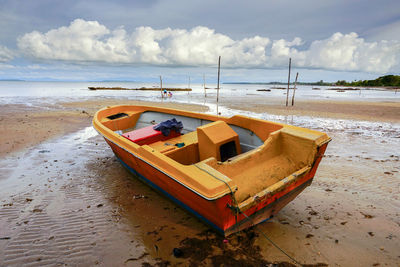 Boat moored on beach against sky