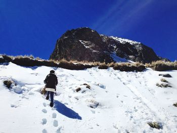 Rear view of a man walking on snow covered landscape