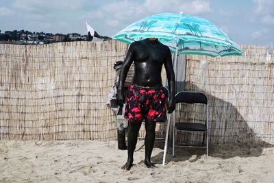 Man with mud on body standing at beach