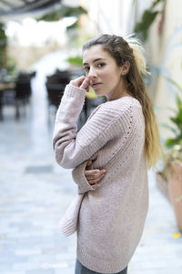 Beautiful teenage girl wearing sweater standing in city