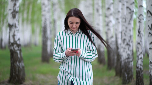 Young woman looking at camera while standing against trees