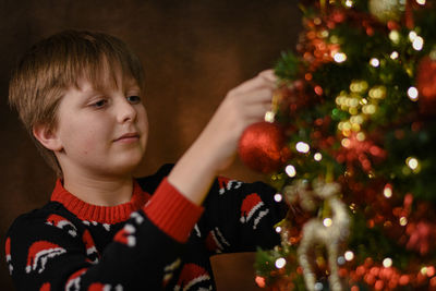 Portrait of cute boy playing with christmas tree