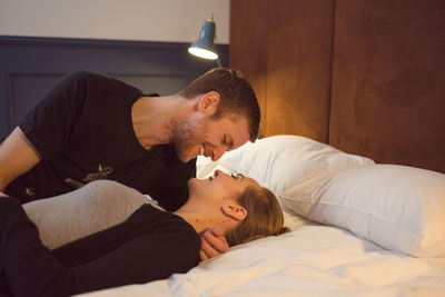 Optimistic couple cuddling on bed
