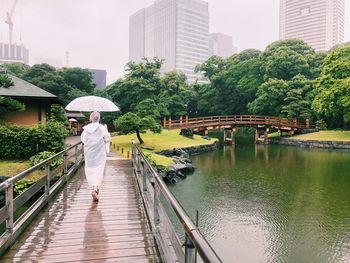 Rear view of woman on footbridge in rainy season