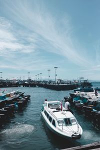 Boats moored at harbor in city against sky