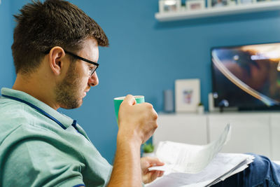 Side view of young man sitting at home