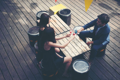 High angle view of friends toasting drinks at bar