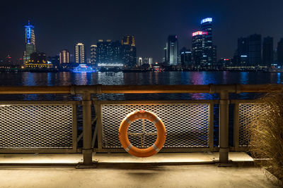 Illuminated buildings by river in city at night