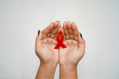 Cropped hand of woman holding heart shape against white background