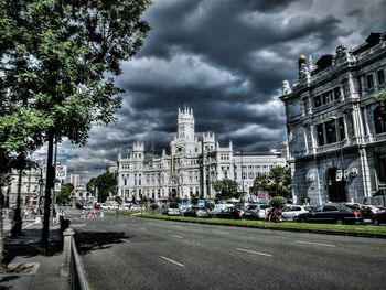 View of city street against cloudy sky