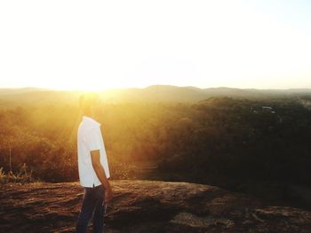 Rear view of man standing on landscape against sky