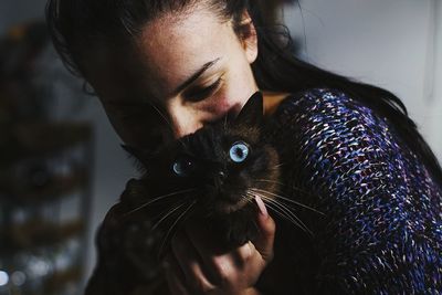 Close-up of young woman holding cat at home