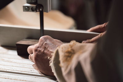 Cabinetmaker cutting piece of wood with electric saw