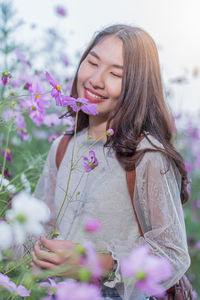 Young woman with pink flowers against blurred background