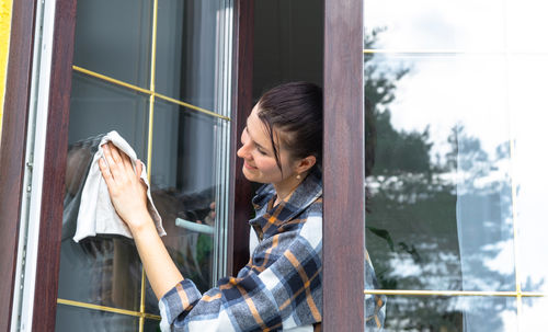 Portrait of young woman looking through window