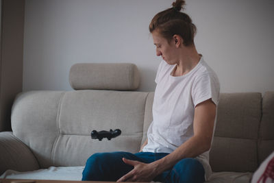 Full length of woman sitting on sofa at home