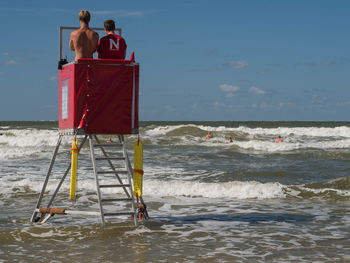 Rear view of people on beach against sky