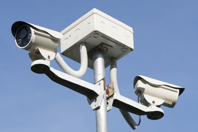 Low angle view of security cameras against sky