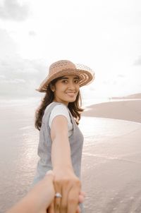 Cropped image of man holding woman hand at beach