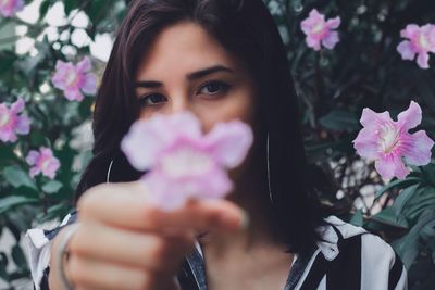 Portrait of beautiful woman holding pink flowering plants