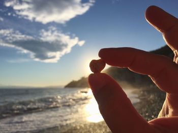 Close-up of hand holding sea against sky during sunset