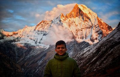 Portrait of woman with snowcapped mountains against sky during winter