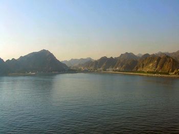 Scenic view of sea by mountains against sky