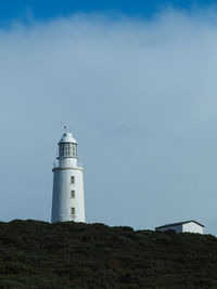 Lighthouse by sea against sky