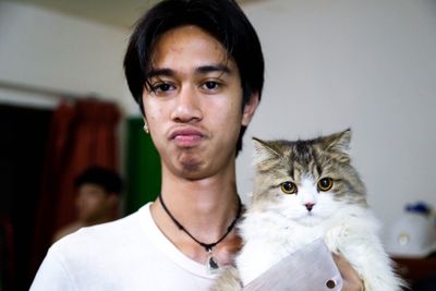 Portrait of young man holding cat at home