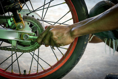 Close-up of hand by bicycle wheel