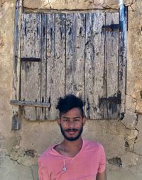 Portrait of young man standing against wall