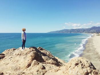 Woman standing on beach against clear sky