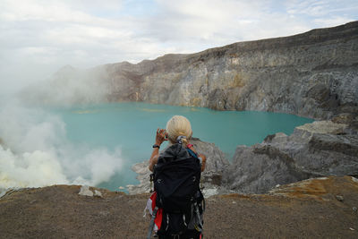 A blonde woman taking pictures at mount ijen.