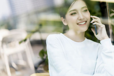 Smiling young woman using mobile phone outdoors