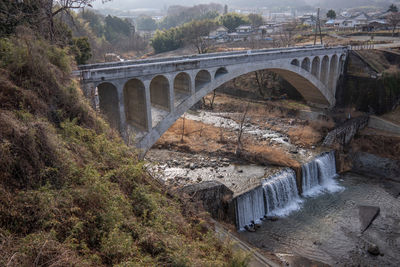 Arch bridge over river against trees