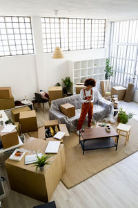 Afro woman writing in notepad while standing in new loft apartment