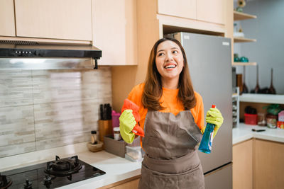 Portrait of smiling young woman standing in kitchen