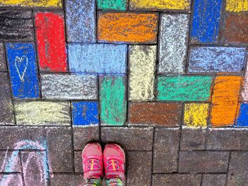 Low section of person standing by multi colored shoes