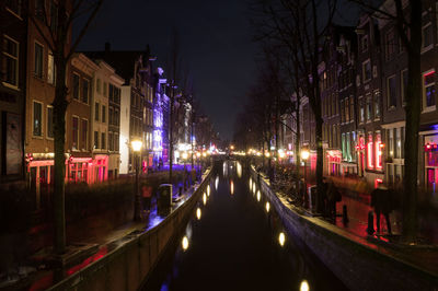 Panoramic view of canal amidst buildings in city at night