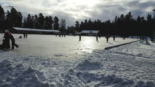 People on snow covered landscape against sky