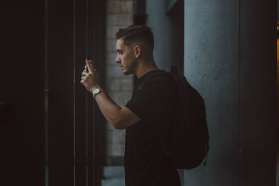 Side view of young man standing against wall