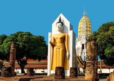 Statue outside temple against building and sky