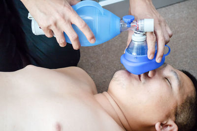 Cropped image of person giving oxygen to man