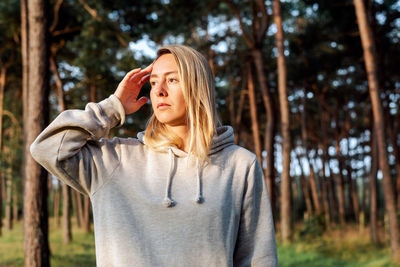 Portrait of a young blond woman walking in a pine forest at dawn.